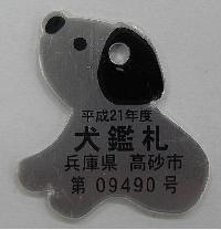 デフォルメされた犬の形をしている灰色の犬鑑札の写真
