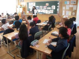 阿弥陀小学校における環境学習の写真で、教室の中でそれぞれの机を教室の中央に向けて並べて講師の話を聞いている。