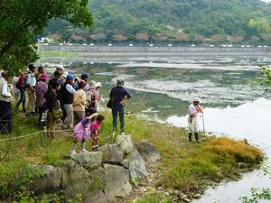 市ノ池のほとりで池を眺める松本先生と参加者たちの写真