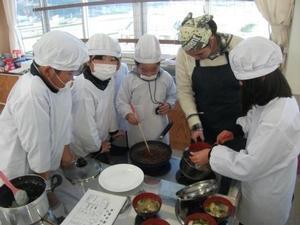 実習中の児童たちの写真。味噌汁が出来上がり、それに使った鰹節のだしがらをプライパンで炒ってふりかけを作っている。