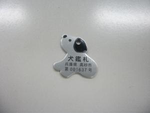 デフォルメされた犬の形をした灰色の犬鑑札の写真
