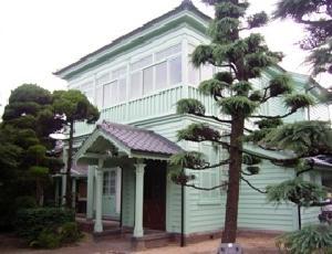 鮮やかな薄緑に塗装された木造の洋館の写真