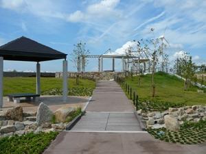 青空の下芝生の丘に舗装された歩道が伸びるあらい浜風公園内の風景写真
