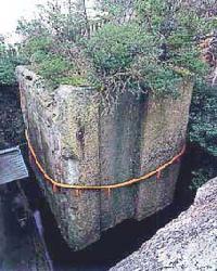 ほぼ正方形の大きな石柱が浮かんでいるように水面に建つ石乃寳殿の写真