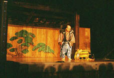 舞台上に一人立っている和服姿の男性の写真