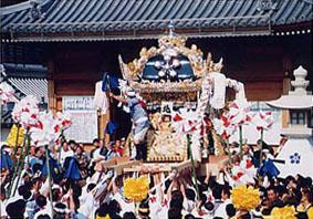 神社の前で神輿の周りに集まる人々の写真