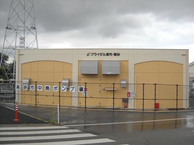 道路と柵を隔てて建つ中島ポンプ場の建物の外観写真