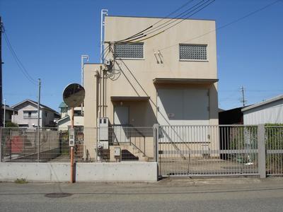 道路に面した場所に建つ小さな建物の藍屋町ポンプ場の外観写真