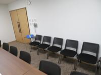 白い壁と椅子が並んだ委員会室の写真