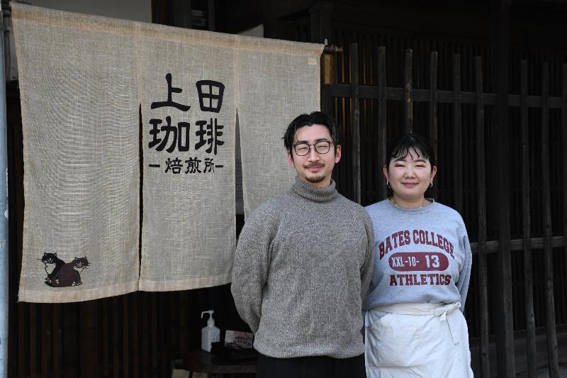 上田珈琲と書かれたのれんの前に立つ男女の写真