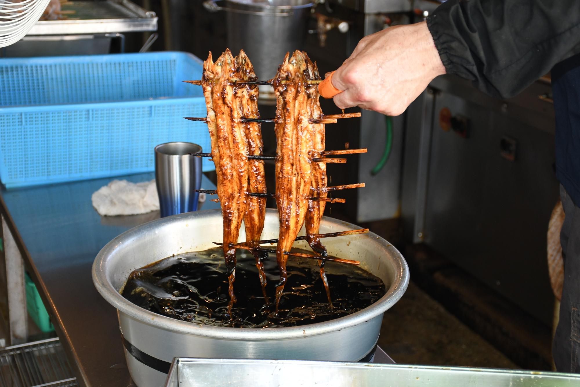 焼きあなごをタレにくぐらせる様子