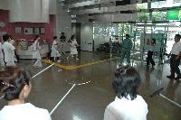 広い屋内にて、壁の三方に沿って並んで刺又の使い方を学ぶ職員たちの写真