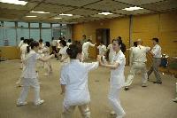 広い屋内にて、2人1組で向き合って並び、素手での護身術を学んでいる職員たちの写真