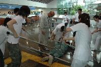 広い屋内にて、床に倒れた1人を数名の職員が刺又で押さえつける訓練の写真