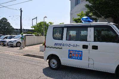 白い車体に青い文字表示と青い回転灯がついている青色防犯パトロール車の写真
