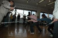 屋内にて、刃物を持った人に数名の職員が刺又で突きを入れる訓練の写真