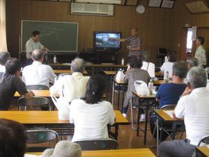 テレビと黒板を用いて行われているまち歩き後の振り返り会議の様子の写真