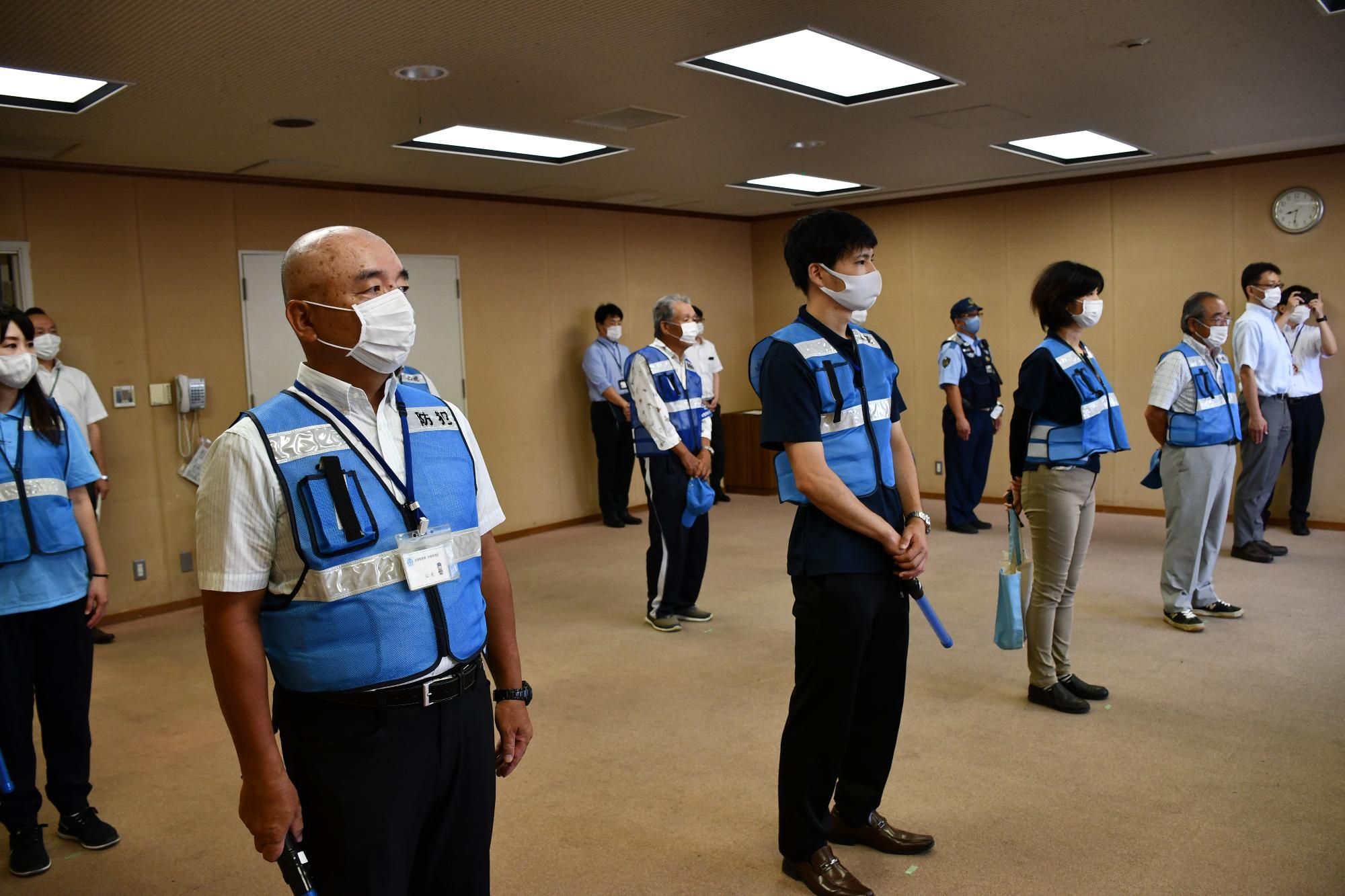 出発式で間隔を空けて並んでいる青色防犯パトロールのメンバーの写真